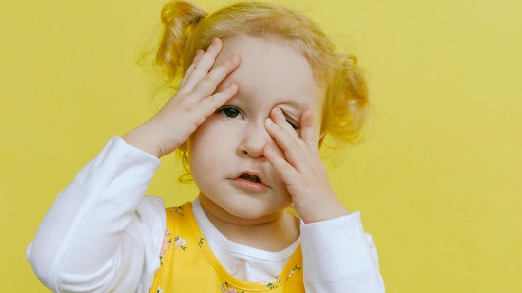 Ein kleines Mädchen hält sich die Hände vor ihr Gesicht. 