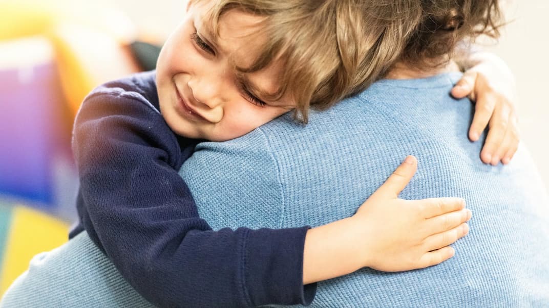 Ein kleiner Junge liegt weinend in den Armen seiner Mutter. 