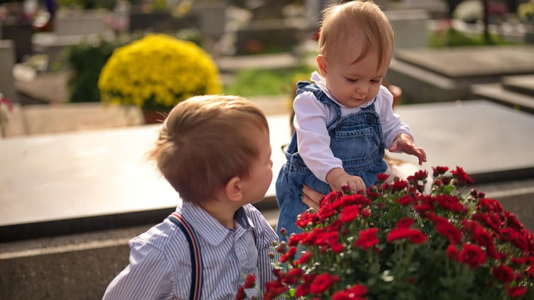 Zwei kleine Kinder auf einem Friedhof. 