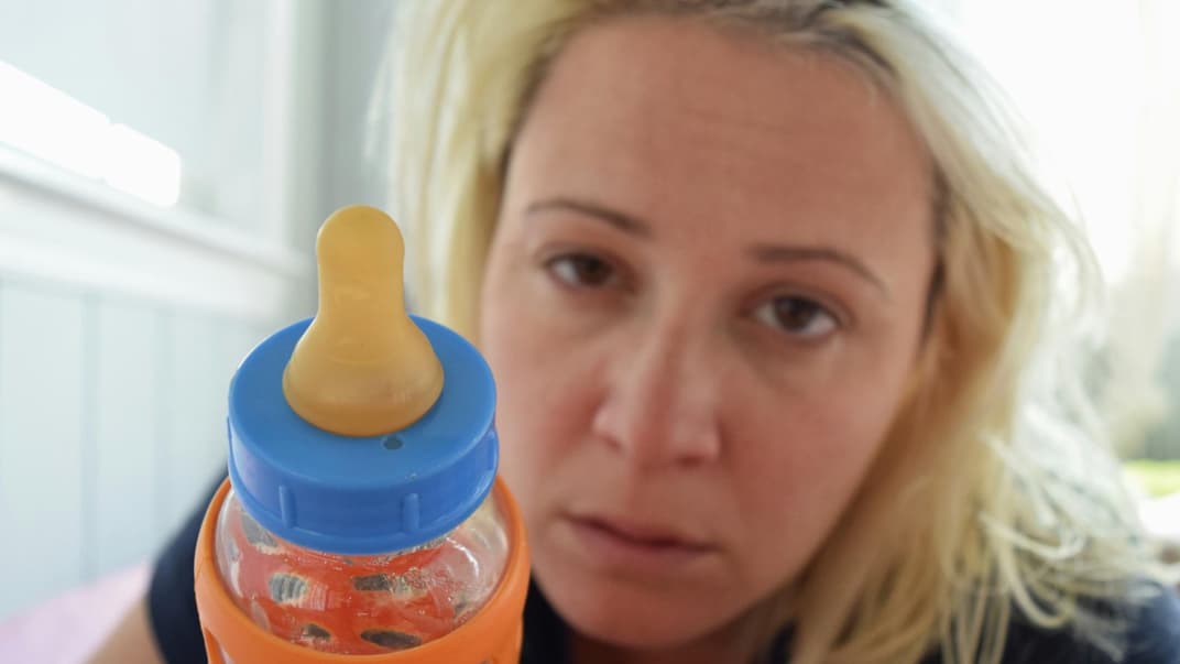 Schlafmangel bei Müttern Eine Mutter, die eine Flasche in der Hand hält ...