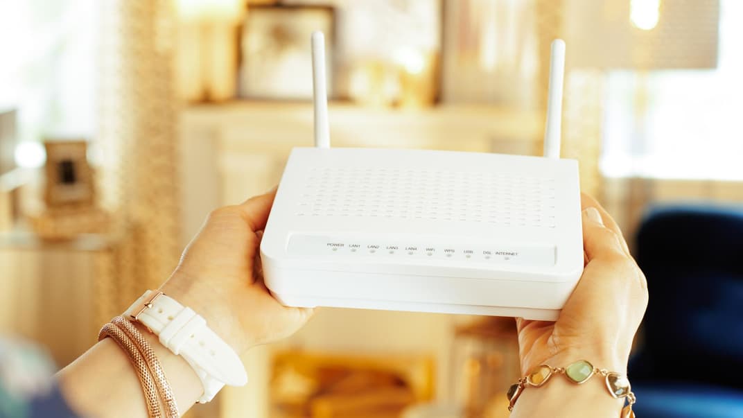 Frau hält einen WLAN-Router in der Hand.