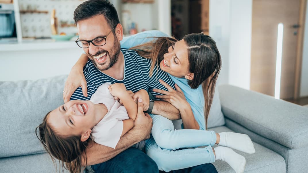 Fröhliche Familie tobt auf dem Sofa.