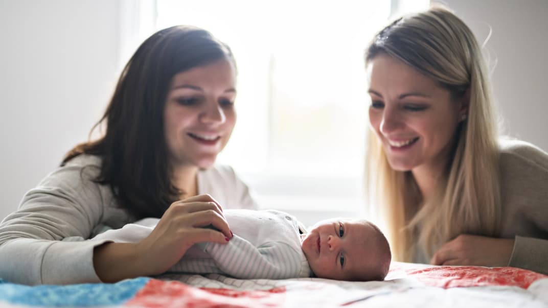 Zwei Frauen lächeln ein Baby an.