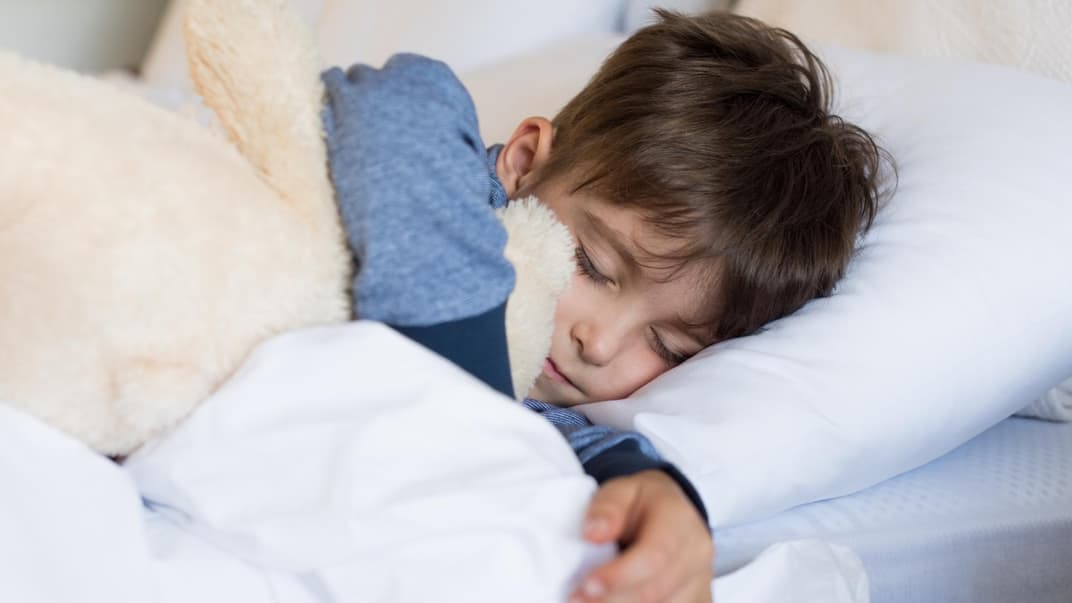 Junge liegt im Bett und schläft.