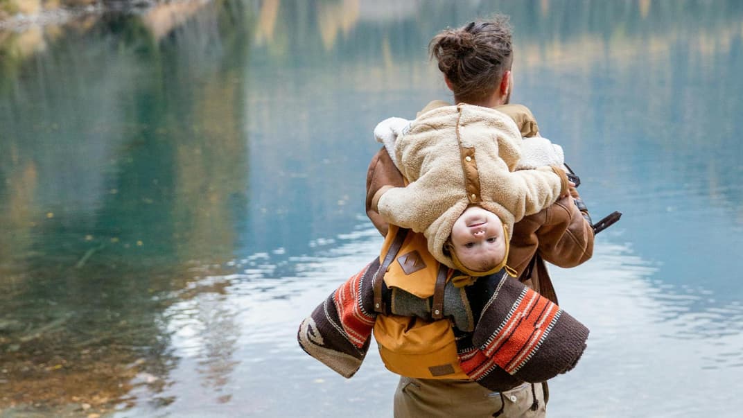 Vater lässt das Baby auf seinem Rücken hängen.