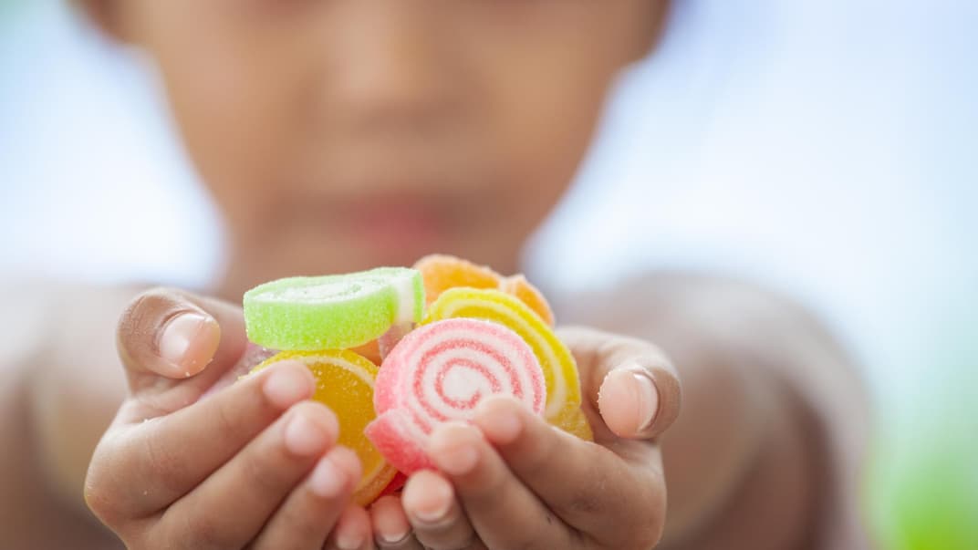 Kind hält Fruchtgummis in der Hand.