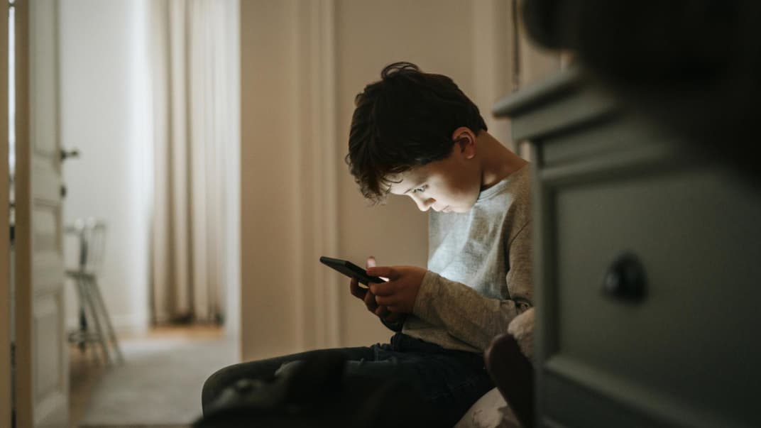 Junge beugt sich über sein Smartphone.