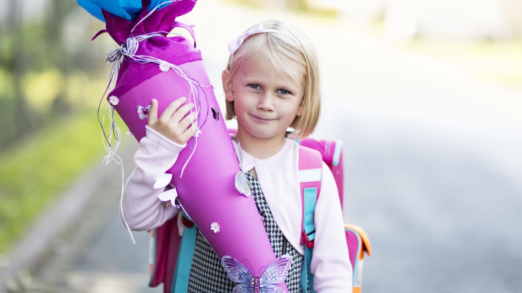 Ein kleines Mädchen hält eine Schultüte in der Hand. 