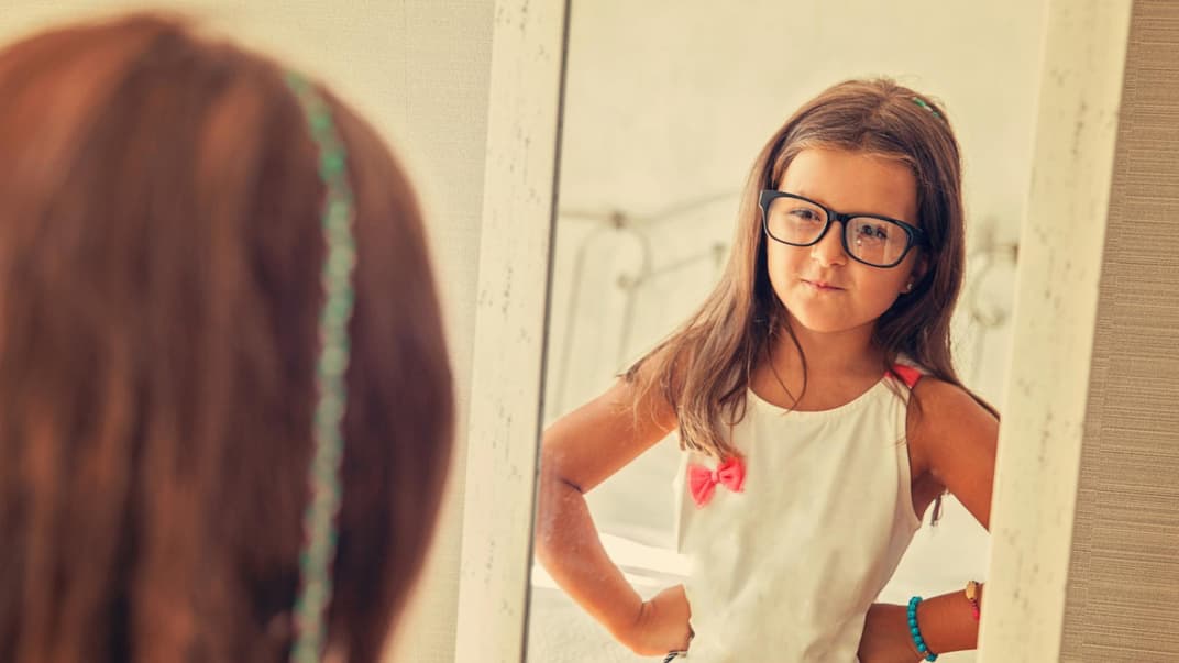 Mädchen betrachtet sich im Spiegel.