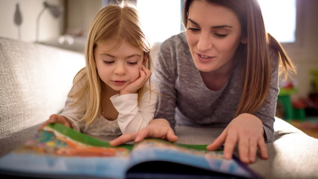 Mutter und Kind lesen gemeinsam auf dem Fußboden.