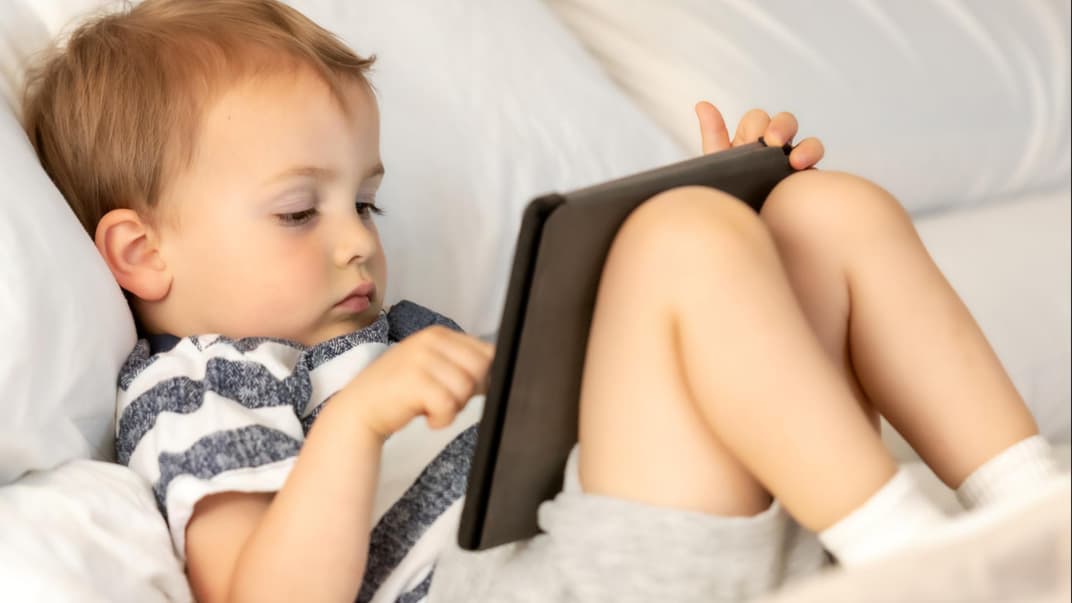 Kleiner Junge sitzt vor einem Tablet.