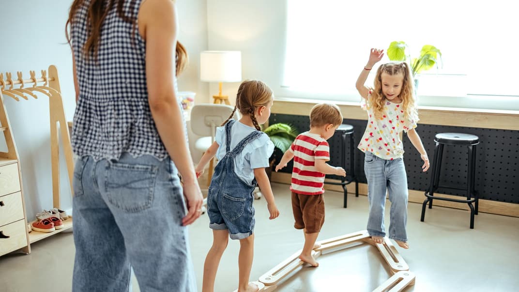 Drei Kinder spielen mit einer Frau.