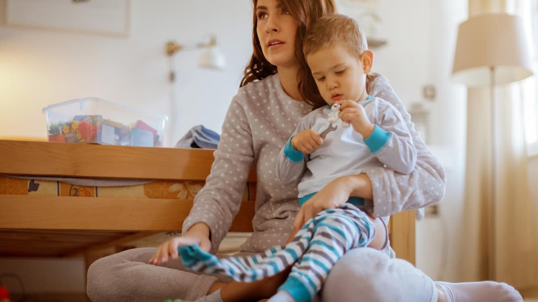 Mutter zieht Kleinkind eine Hose an.