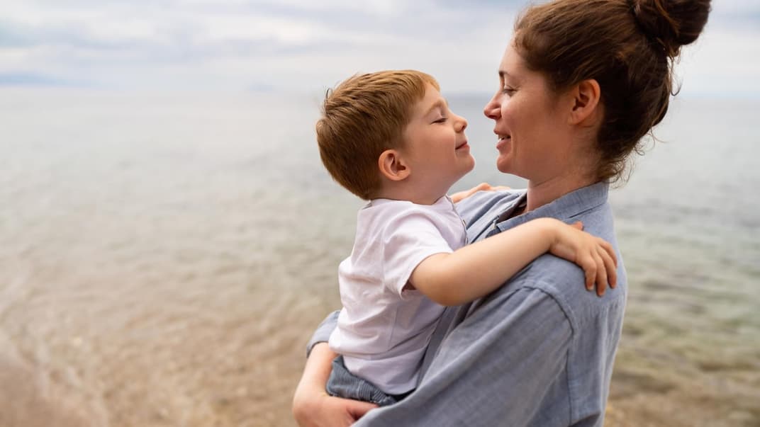 Mutter hält Sohn am Strand im Arm
