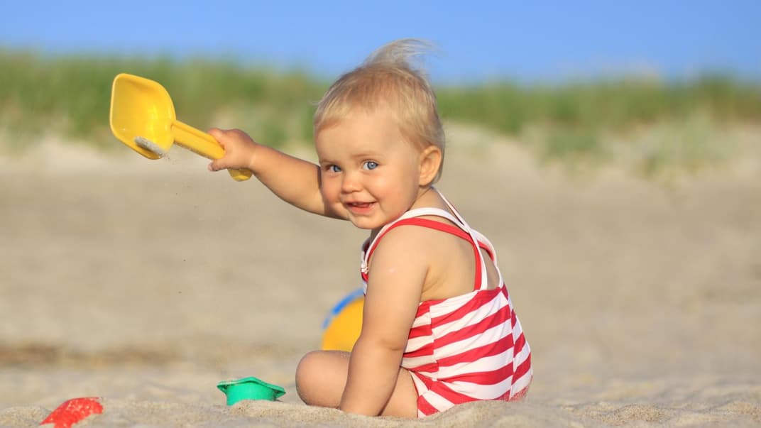 Ein Baby, das am Strand buddelt. 