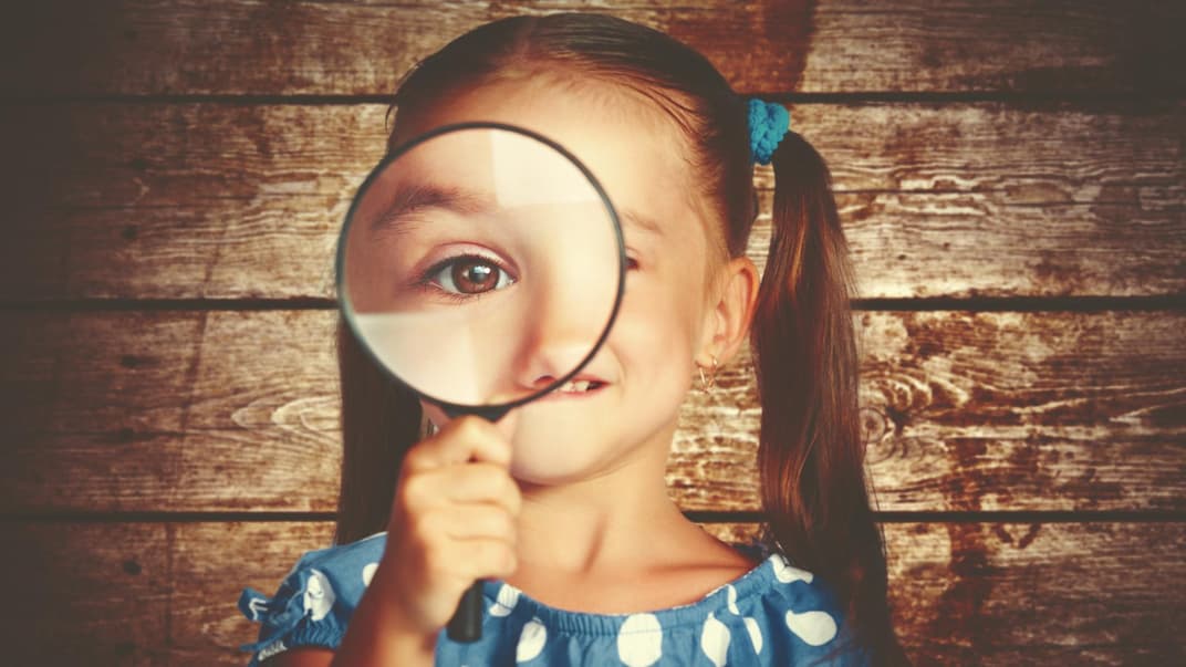 Mädchen schaut durch eine Lupe.