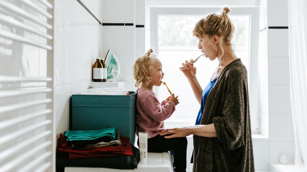 Mutter und Kind putzen gemeinsam die Zähne.