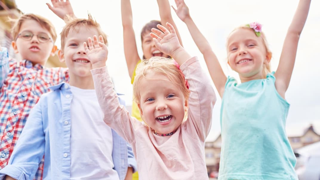 Lachende Kinder mit erhobenen Armen.