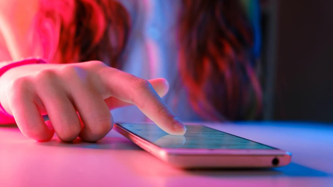 Jugendliche wischt mit dem Finger übers Smartphone.