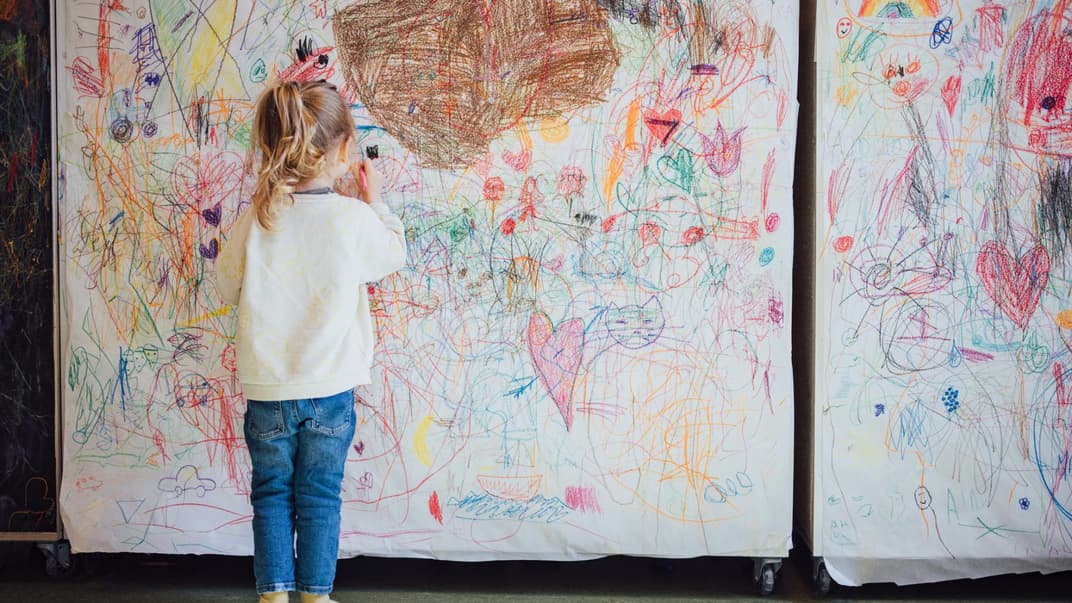 Kleines Kind malt eine Stellwand voll. 