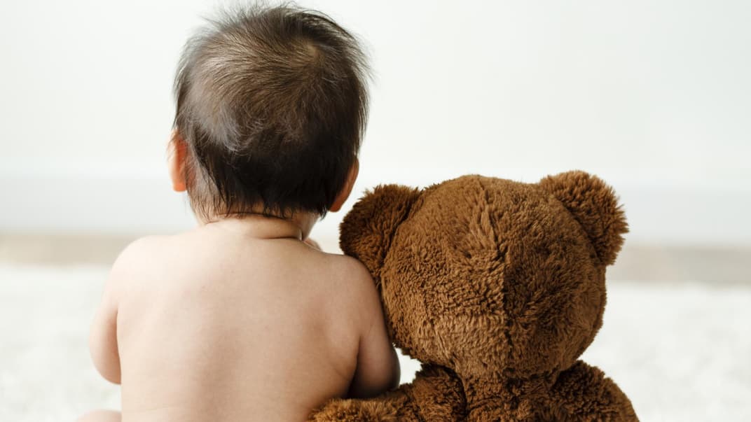 Baby und Kuschelbär mit Windeln.
