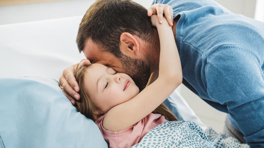 Kind umarmt seinen Vater beim Ins-Bett-Gehen.