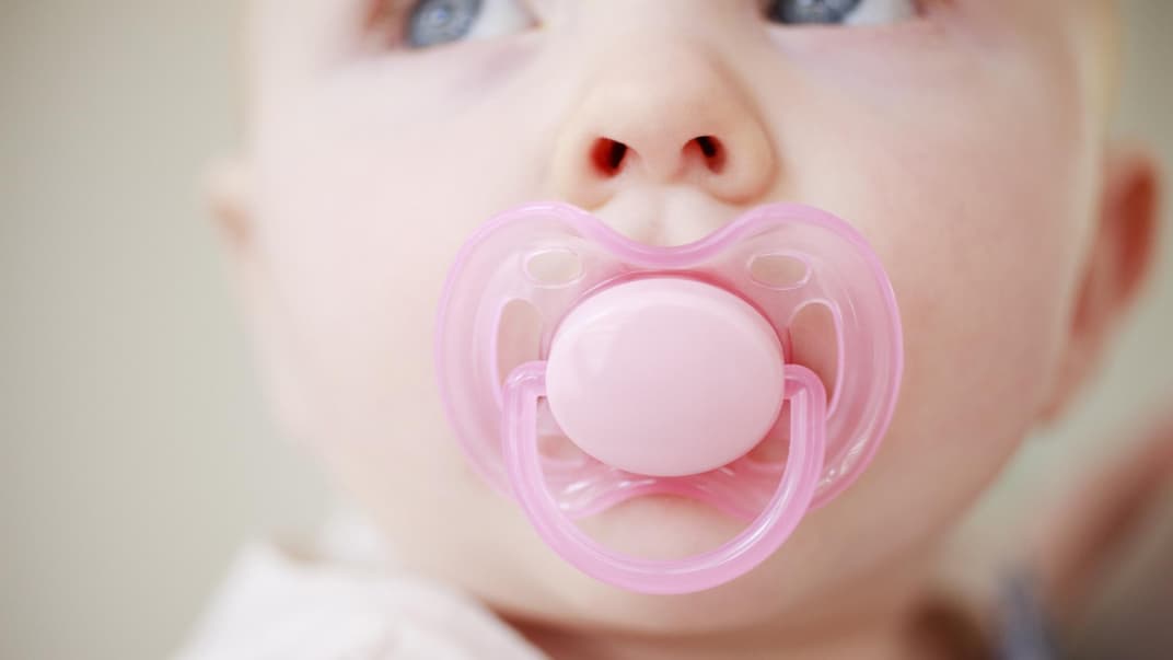 Baby mit Schnuller im Mund.