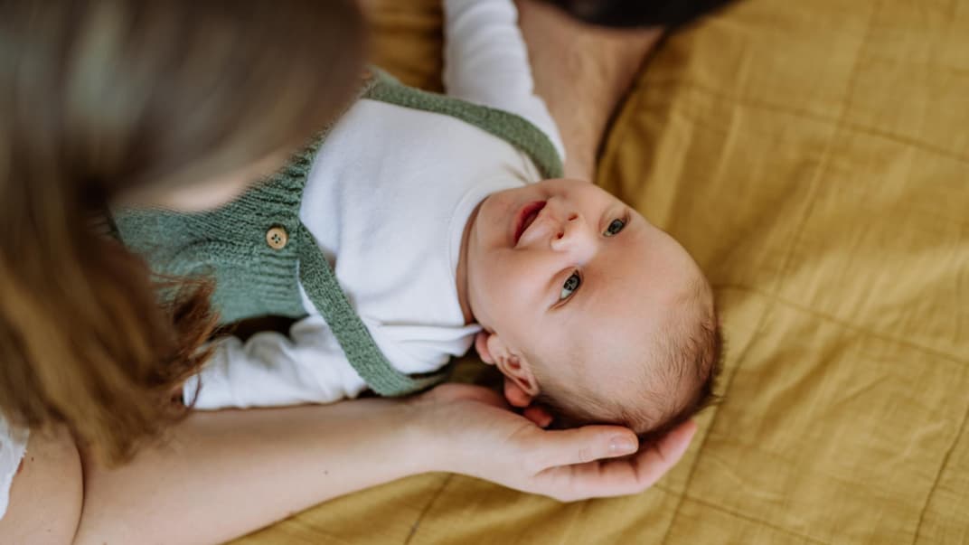 Eltern beugen sich über ihr Baby.