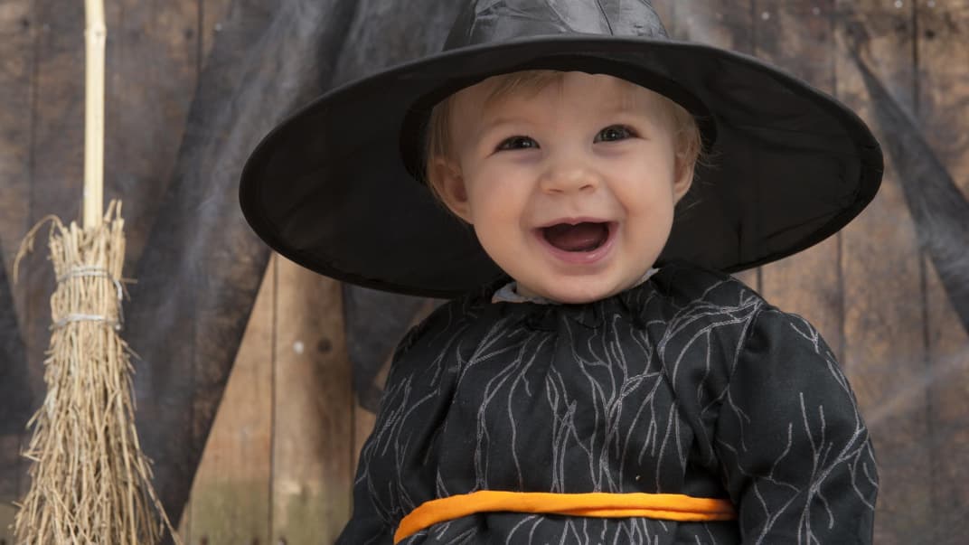 Kleinkind an Halloween mit Hexenkostüm.