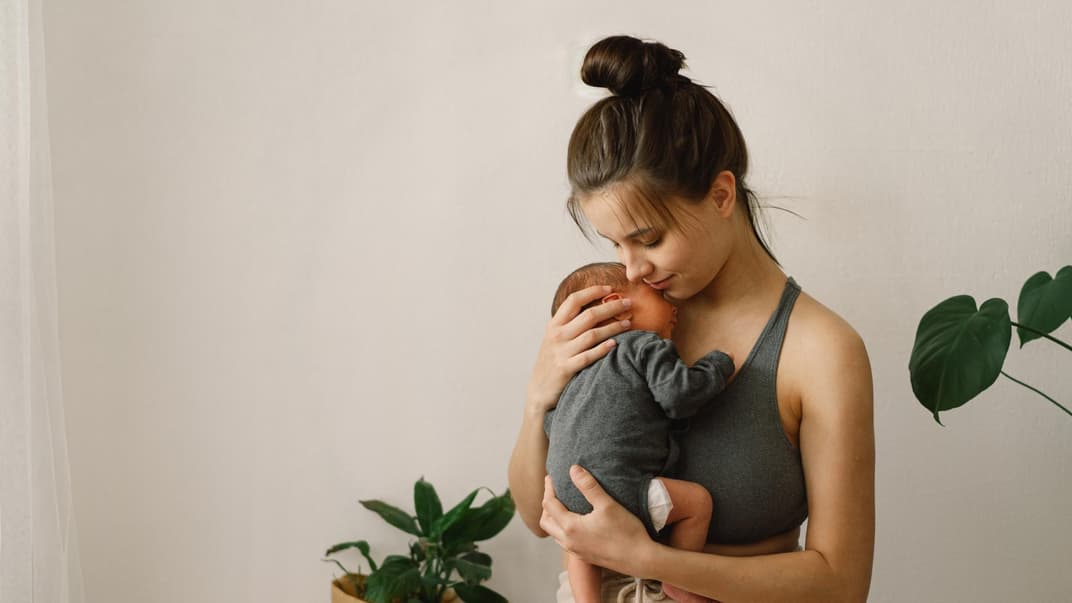 Mutter trägt Baby im Arm.