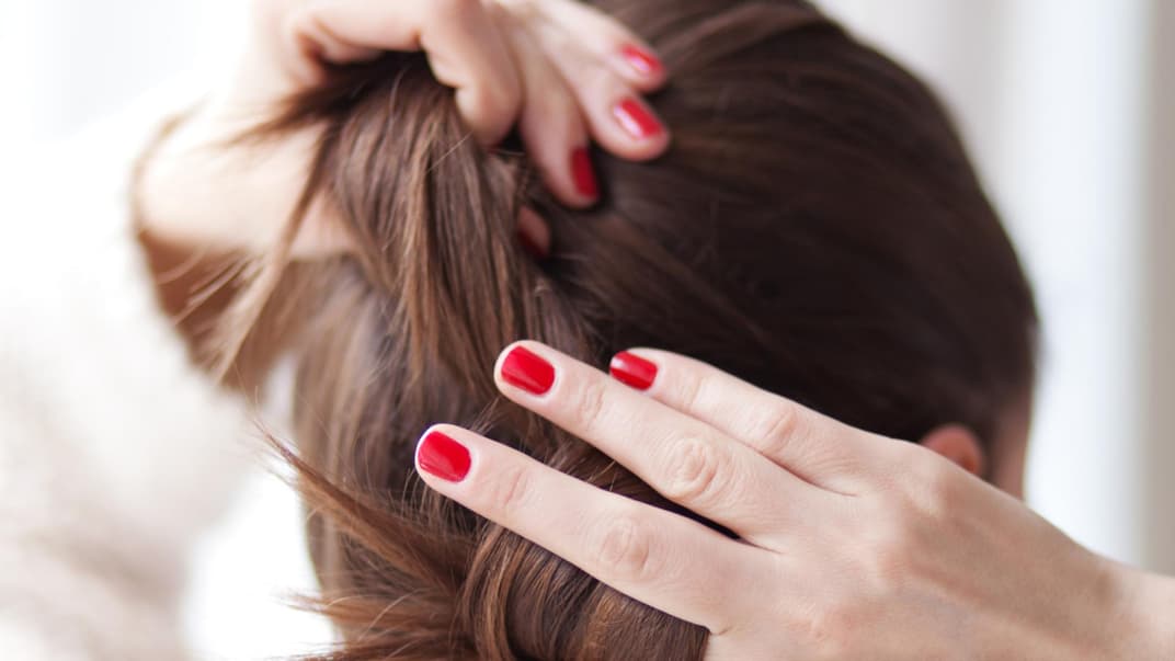 Eine Frau dreht eine Dutt-Frisur.