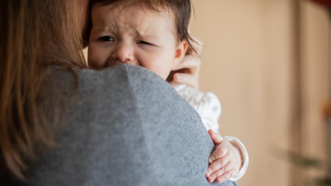 Baby weint auf Mamas Arm.