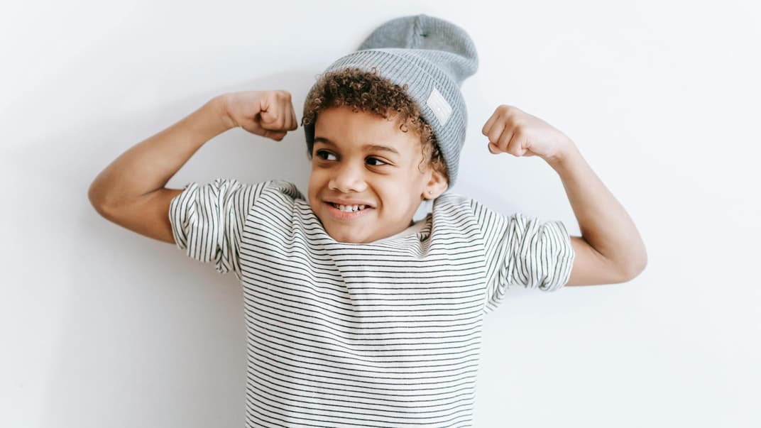 Junge, der seine Muskeln stark macht.