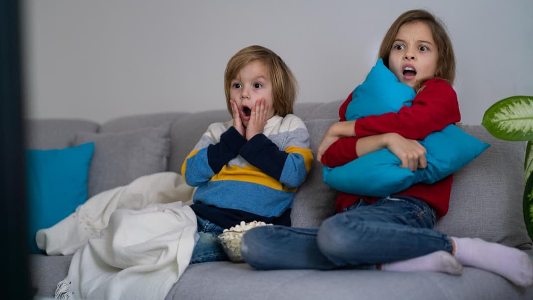 Zwei kleine Kinder fürchten sich vor dem Fernseher. 