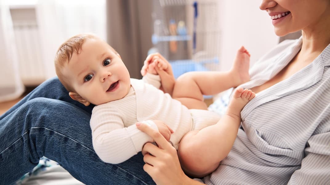 Lachendes Baby auf dem Schoß der Mutter.
