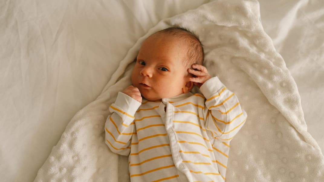 Neugeborenes liegt auf der Decke.
