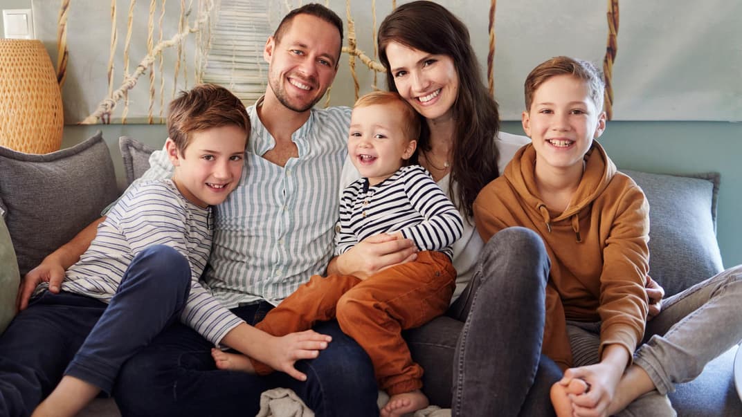 Familie mit drei Kindern sitzt auf dem Sofa.
