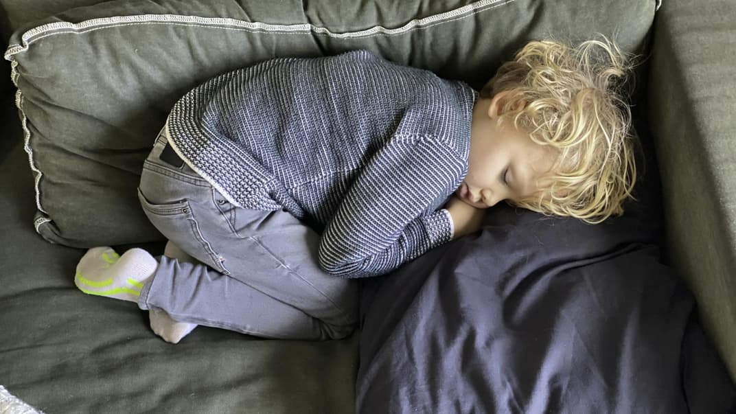 Kind hält Mittagsschlaf auf dem Sofa.