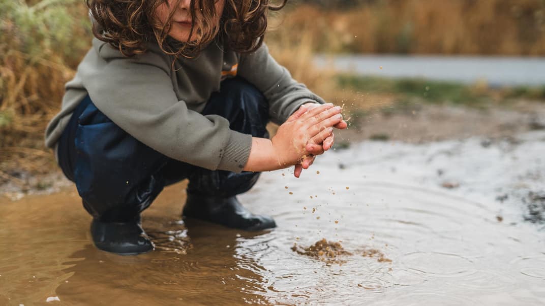 Kind spielt in einer Pfütze