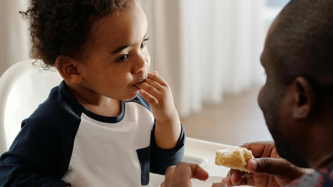 Ein kleiner Junge leckt sich die Finger ab. 