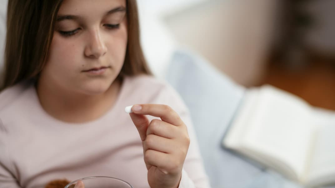 Ein Mädchen nimmt eine Paracetamol Tablette. 