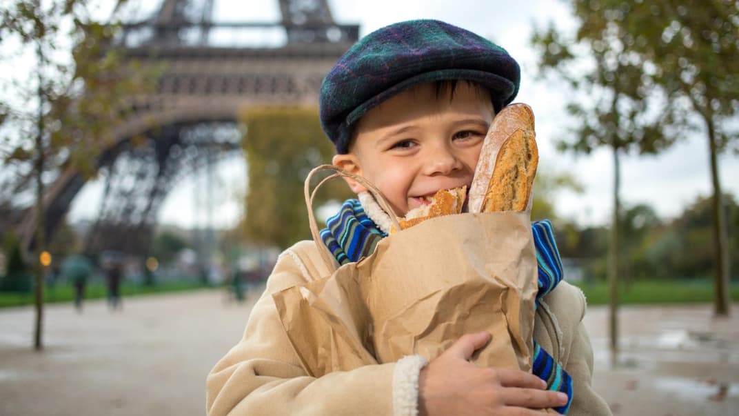 Ein Kind in Frankreich mit Baguettes in der Hand