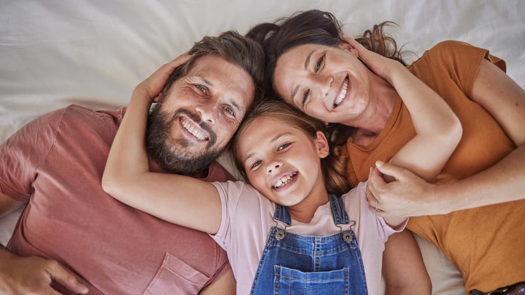 Glückliche Familie liegt im Bett.