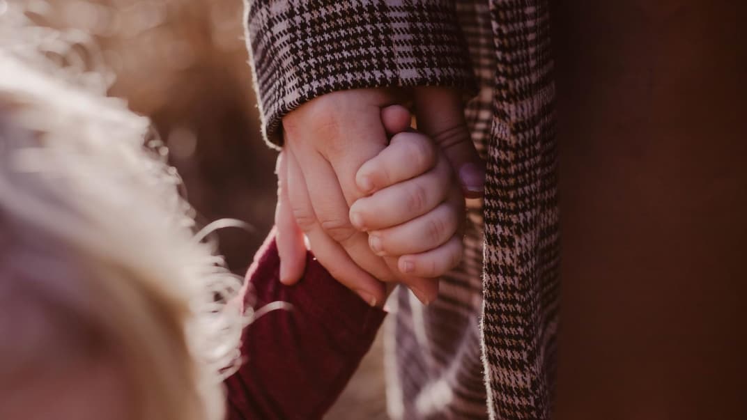 Mutter und Kind halten Händchen.