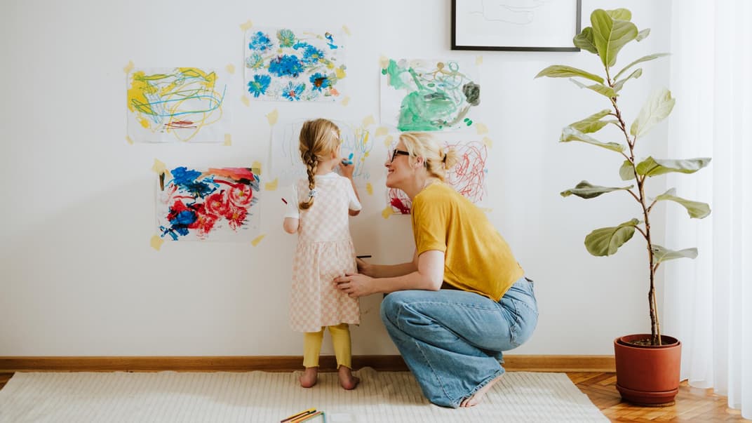 Kind malt, Mutter schaut zu.