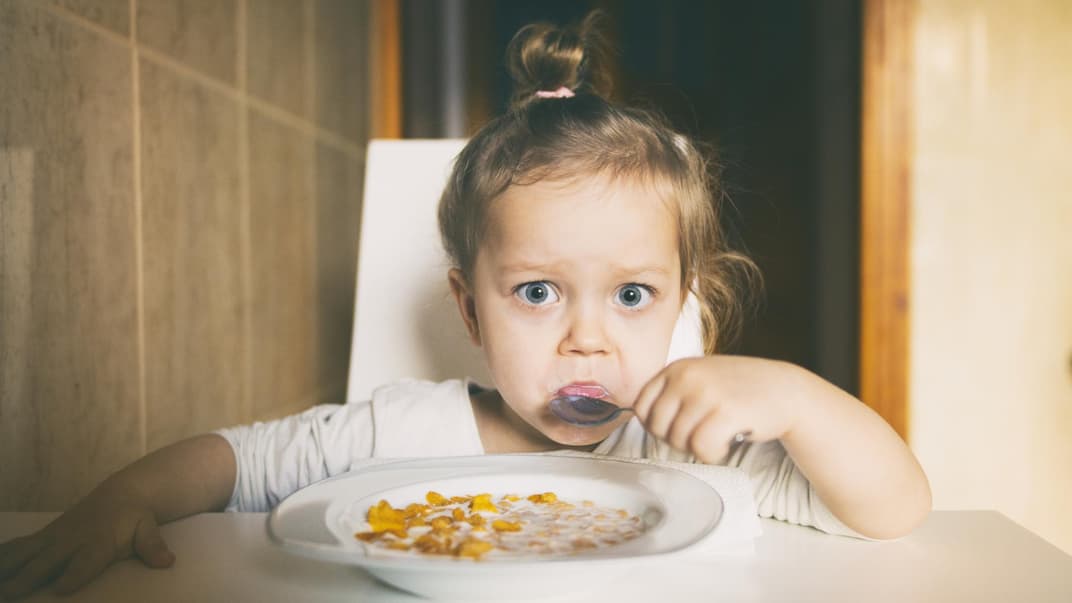 Kleines Mädchen isst Müsli.