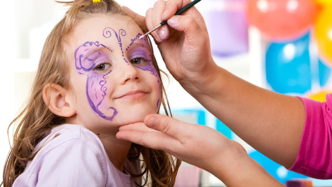 Mädchen wird als Schmetterling geschminkt.