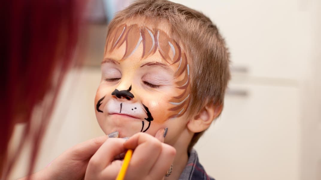 Kleiner Junge, dem ein Löwengesicht geschminkt wird.