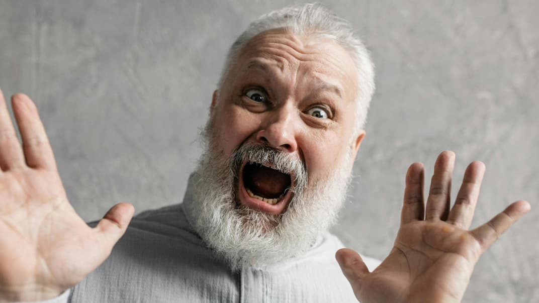 Lachender Opa, der die Hände in die Luft hebt.