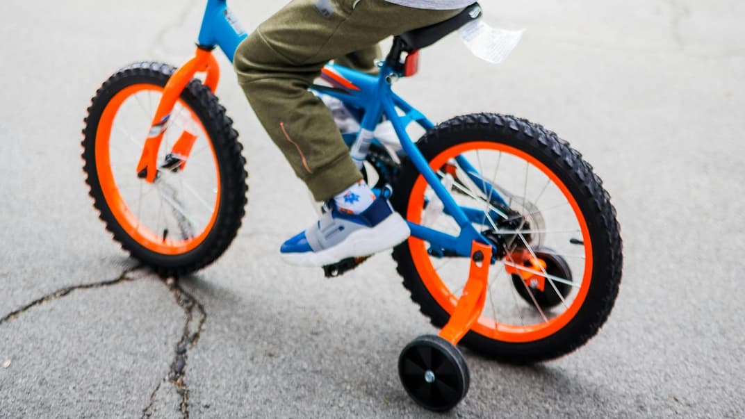 Ein Kind auf einem Fahrrad mit Stützrädern 